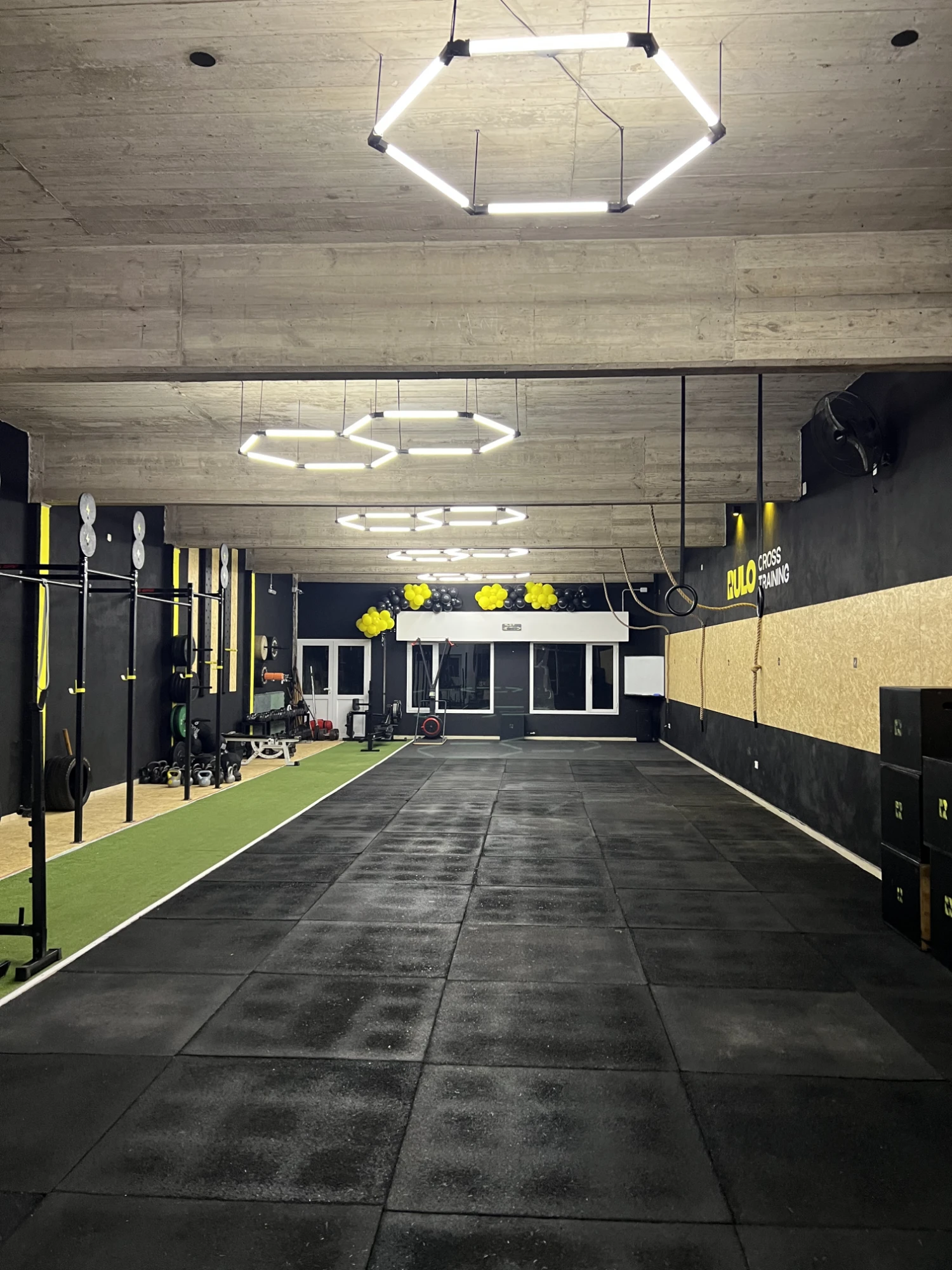 Vista general del box: piso de goma, pista de césped, racks y luces hexagonales